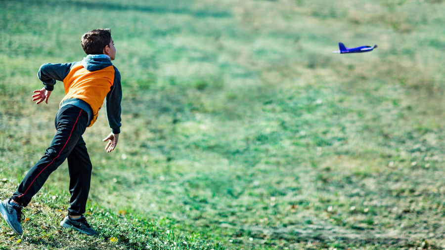 Boy playing with toy glider airplane outdoors on the field
