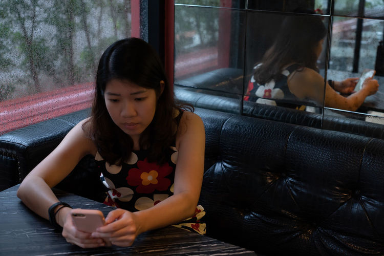 Woman using smart phone while sitting at cafe