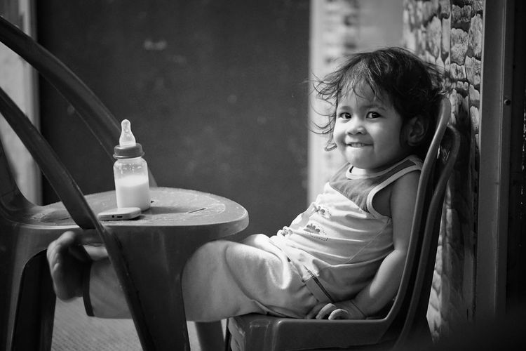 Portrait of cute baby girl sitting on chair at home