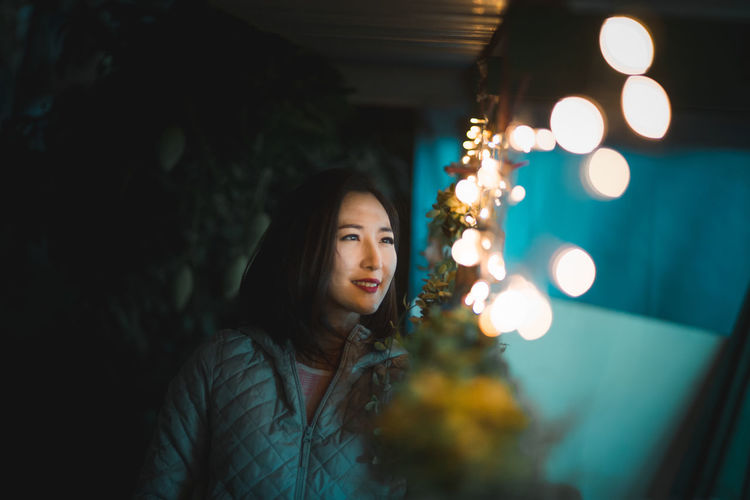 Woman looking at illuminated string lights at night