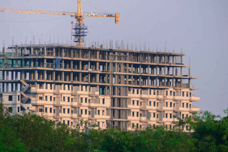 View of building by construction site against sky