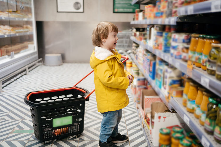 Child in the market with a grocery cart, chooses a product