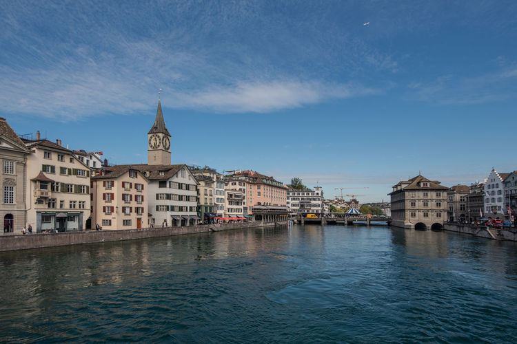 Buildings at waterfront against blue sky