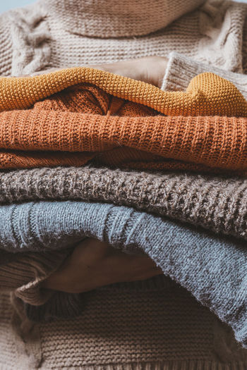 Cropped shot of a female holding knitted warming sweaters. preparing clothes for coming cold season