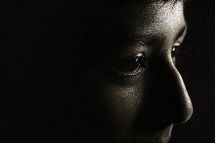 Close-up of boy against black background