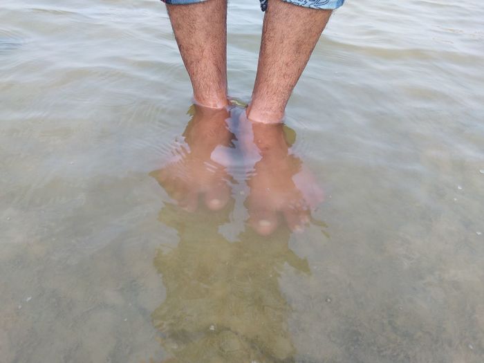 Low section of man standing in water
