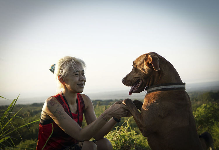 A woman shaking hand with the dog.