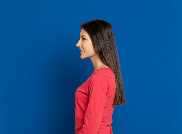Side view of a young woman against blue background