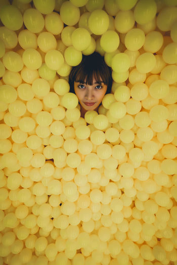 High angle portrait of smiling young woman lying in ball pool