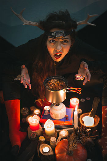 Close up woman shaman with horns grimacing above pot portrait picture