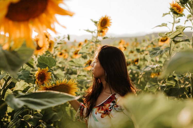Young woman with eyes closed standing amidst sunflowers