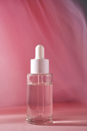 Transparent bottle of cosmetic gel on a pink background.