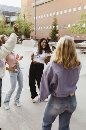 Happy female teenager friends dancing at skate park
