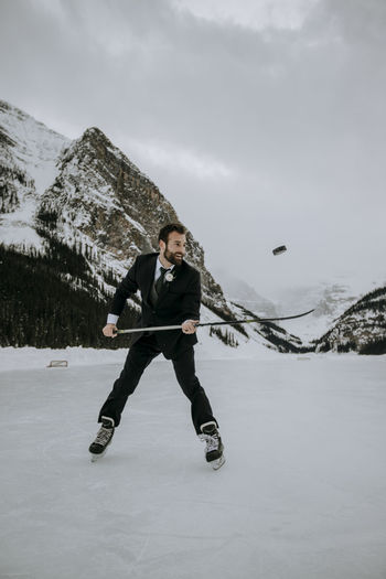 Hockey player with suit on juggles puck on frozen lake in mountains
