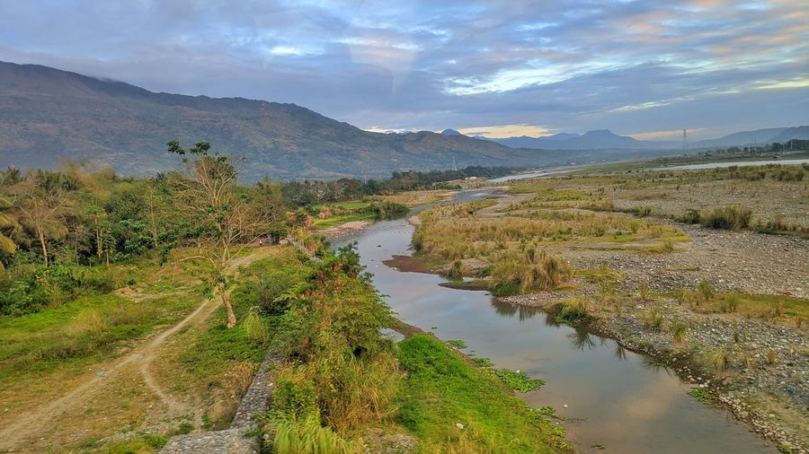 Scenic view of river by mountains against sky