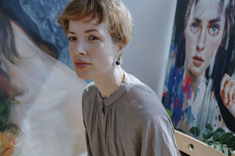 Female artist looking away against painting in art studio