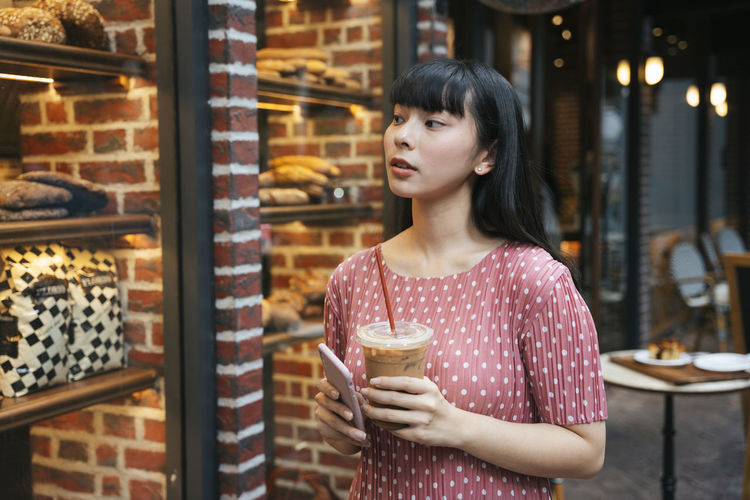 Young woman looking away while standing at store