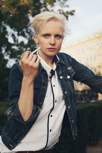 Mid adult woman holding cigarette in park