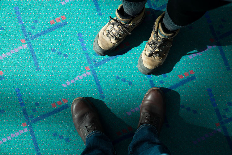 Low section of people wearing shoes standing on carpet