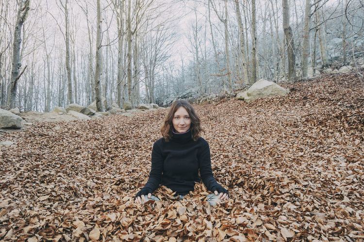 Woman enjoying autumn and catching falling yellow leaves