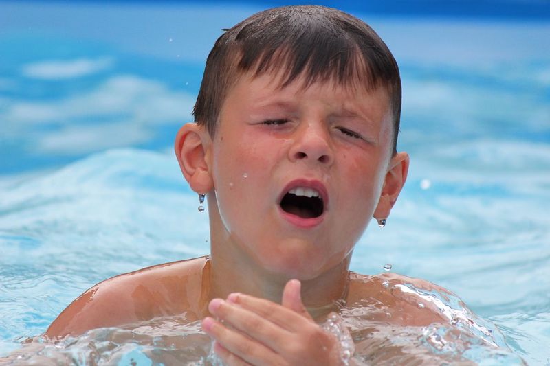 Close-up of boy sneezing in swimming pool
