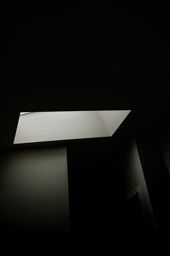 Low angle view of illuminated lamp on wall in building