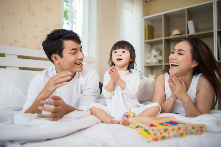 Family playing with toys on bed at home