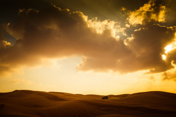 Scenic view of dramatic sky over desert landscape with car