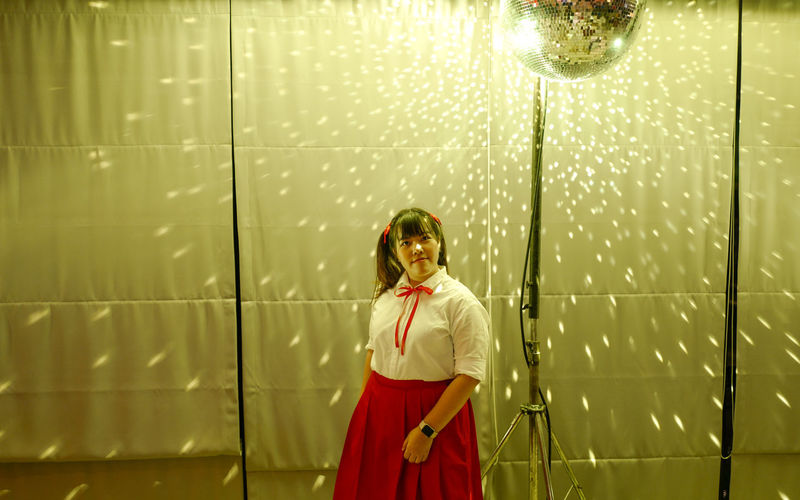 Portrait of woman standing against illuminated backdrop