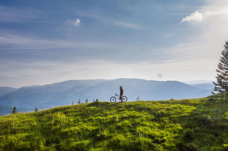 Man riding bicycle on grassy field against sky