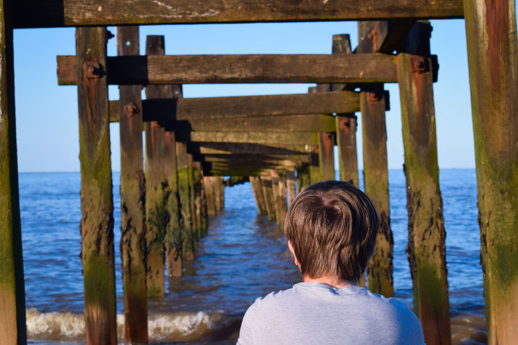 Rear view of boy looking at pier