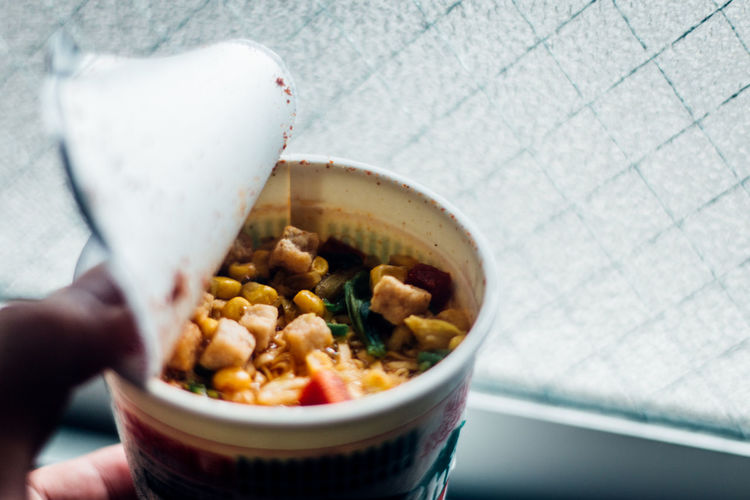 Close-up of hand holding ice cream in bowl
