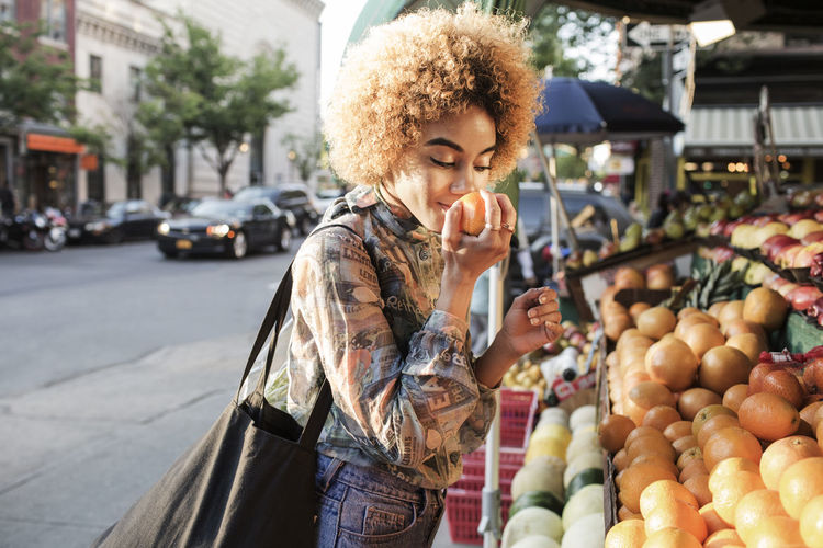Woman smelling fresh orange at market stall