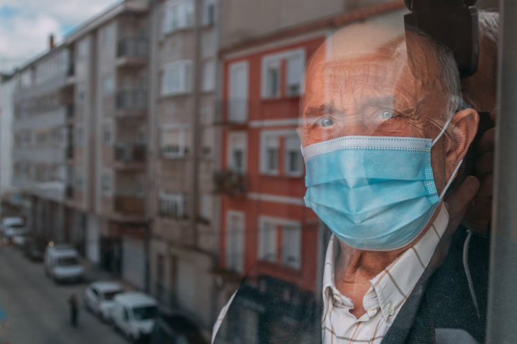 Portrait of man wearing mask looking through window
