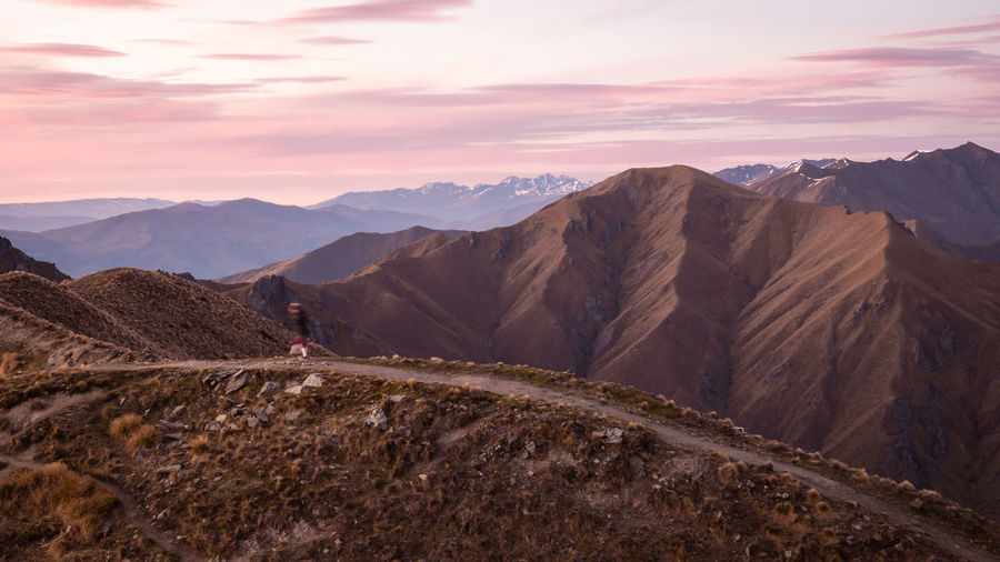 Person walking on the mountain trail during sunrise. roys peak summit in wanaka, new zealand