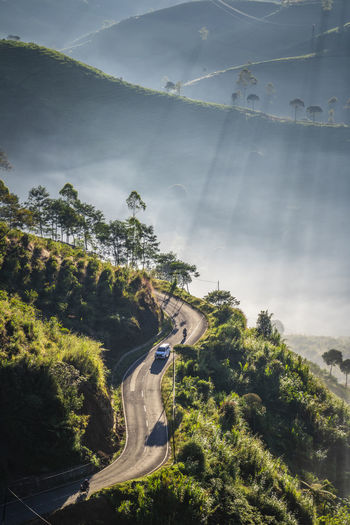 High angle view of winding road and  foggy valley against ray of sun light in the morning