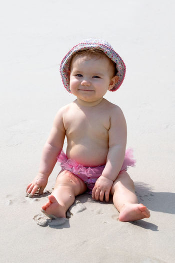 Smiling little baby girl playing with sand at beach. sensory development for kids. 