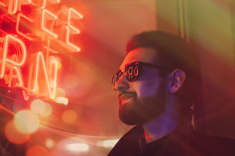 Young man wearing sunglasses in illuminated club