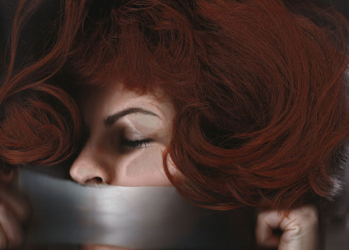 Close-up of young woman covering mouth with adhesive tape