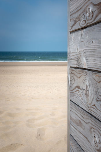 Summertime picture with gray patina wood in front of sandy beach and blue sky