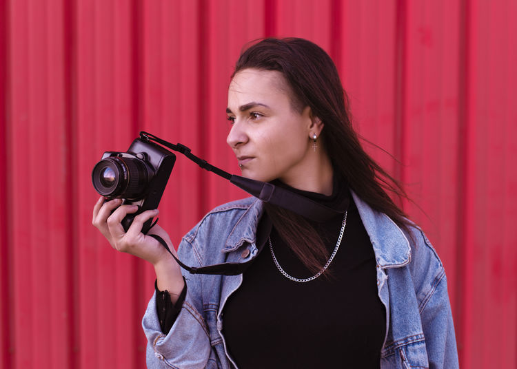 Young woman photographing with red camera