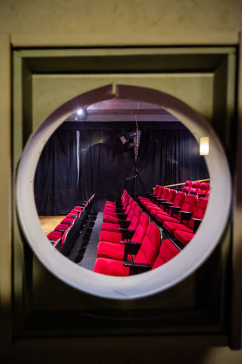 Porthole view into a cinema with red chairs