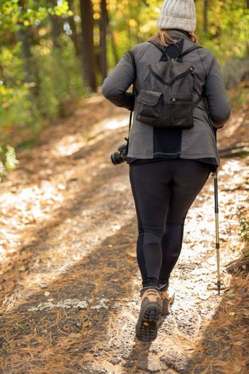 Rear view of woman walking on footpath in forest