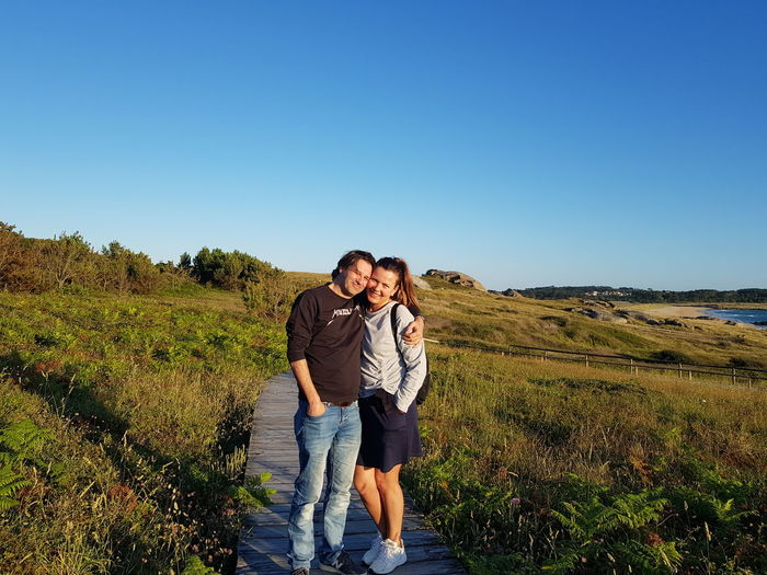 Full length of couple on landscape against clear blue sky