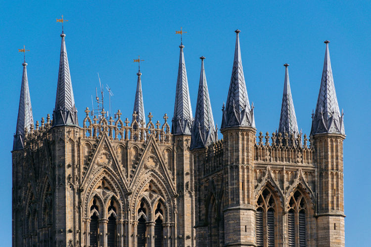 Low angle view of lincoln cathedral towers against blue sky