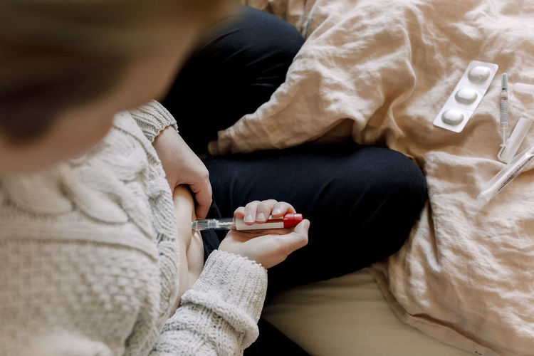 side view of girl using mobile phone while lying on bed at home