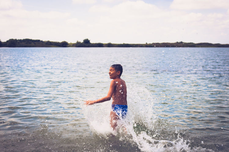 Carefree boy having fun in summer day and rushing in the water at the beach. copy space.