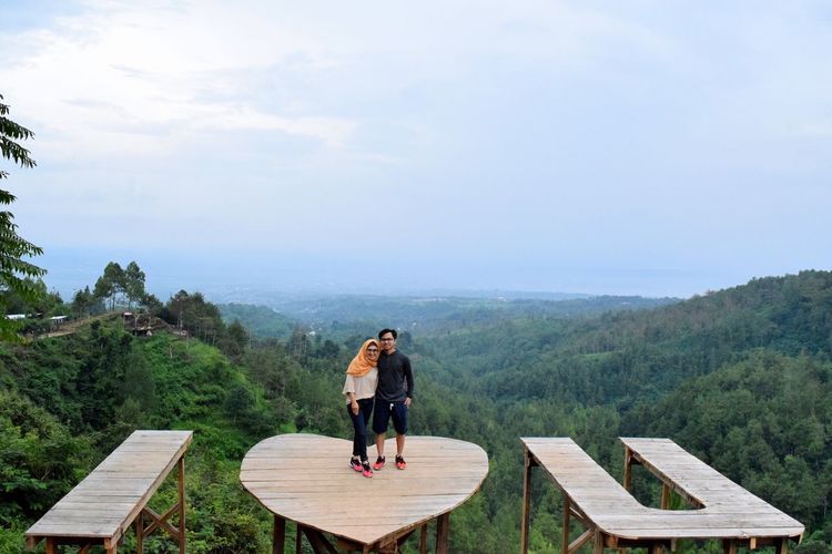 Couple standing on heart shape table against sky