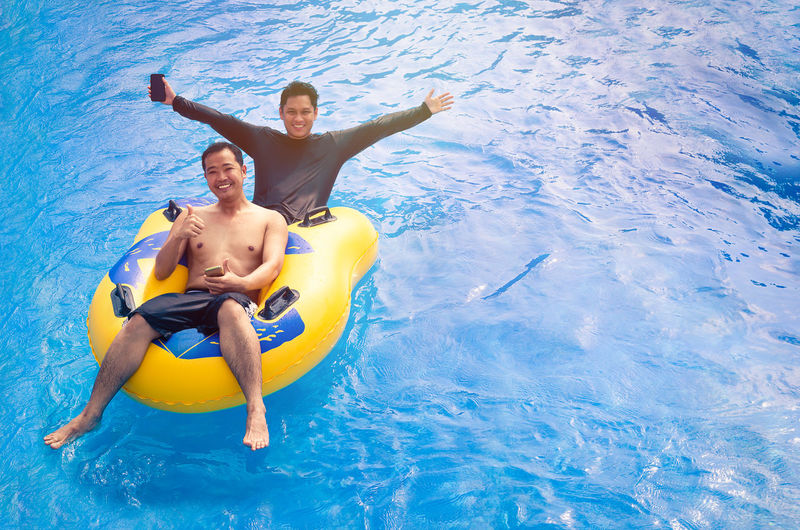 Full length of happy young man in swimming pool