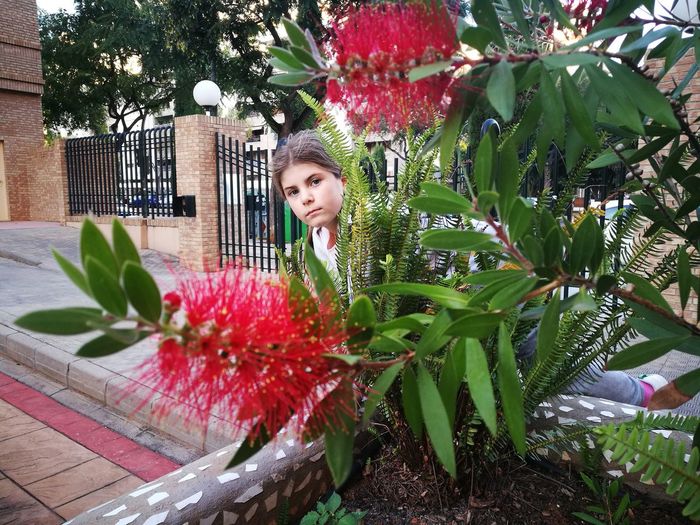 Girl standing against red flowering plant